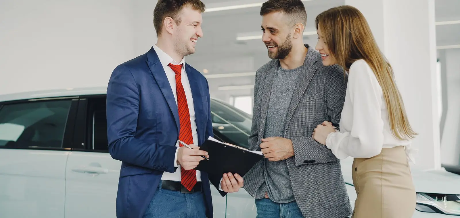 A car salesperson showing a new vehicle to a couple on a dealership showroom floor