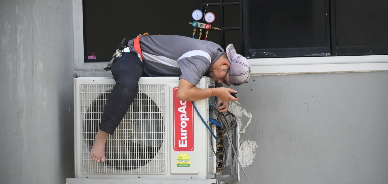 An HVAC technician servicing an outdoor air-conditioning condenser unit