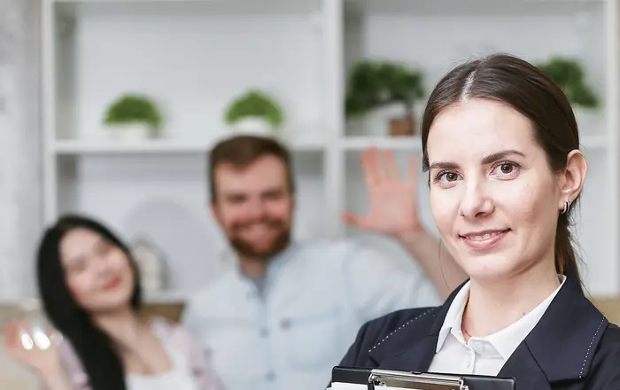 An insurance agent holding a home-insurance policy while meeting a family