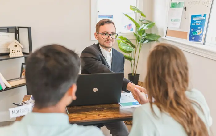 A loan officer reviewing mortgage options with a couple at a desk