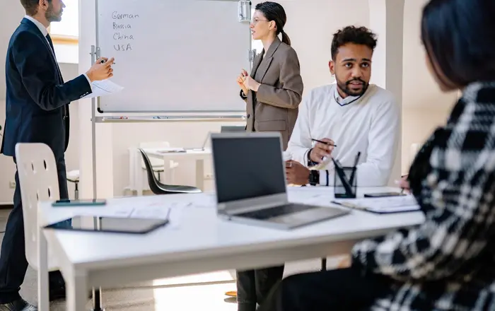 A B2B software team collaborating around laptops and a whiteboard in an office