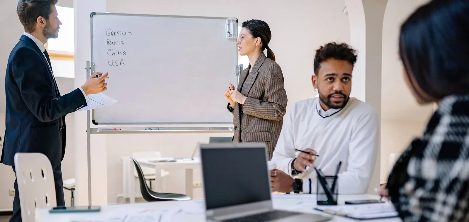 A B2B software team collaborating around laptops and a whiteboard in an office