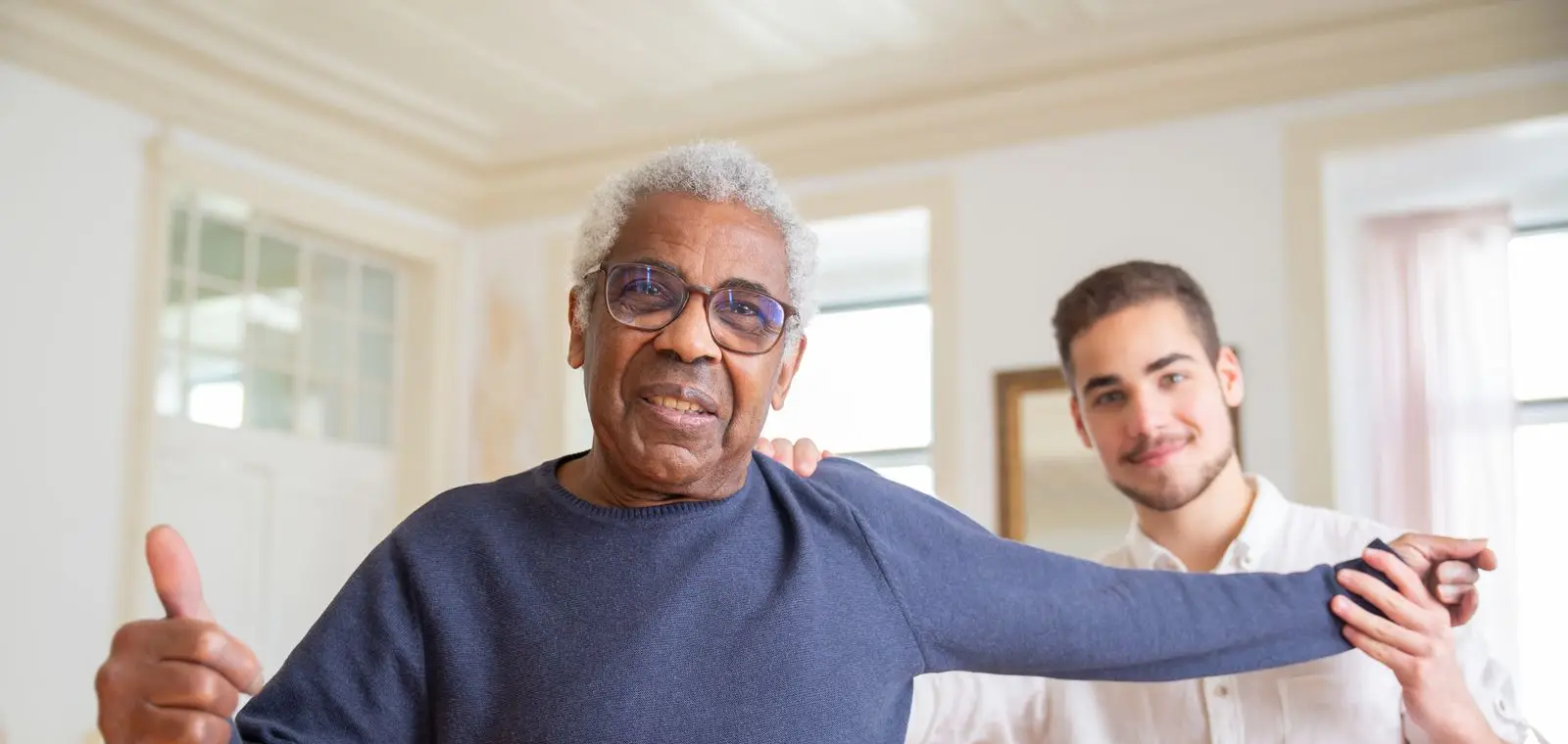 A caregiver supporting a smiling senior man at home